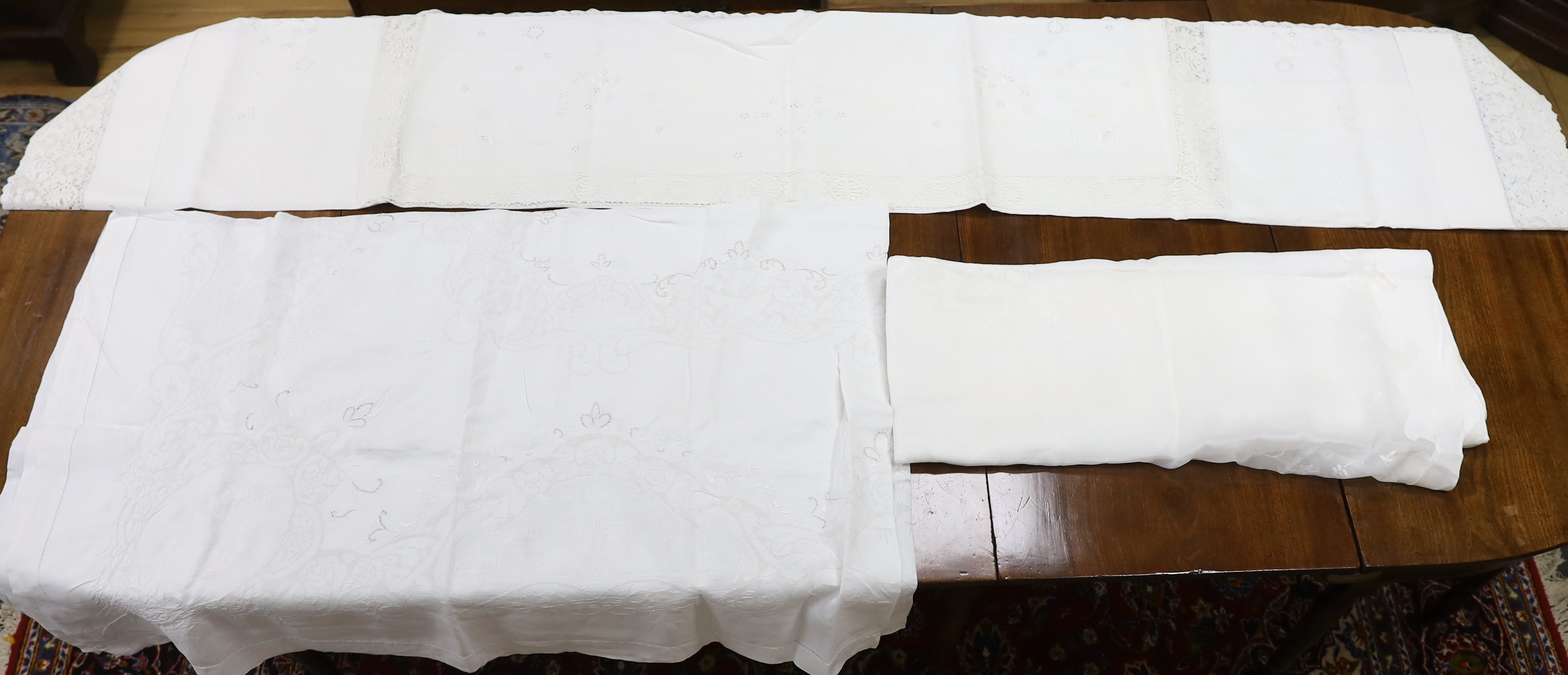 Table linen; A large linen embroidered and finely worked table cloth, an Anglaise worked cloth with crochet border and a fine appliqué cloth (3)